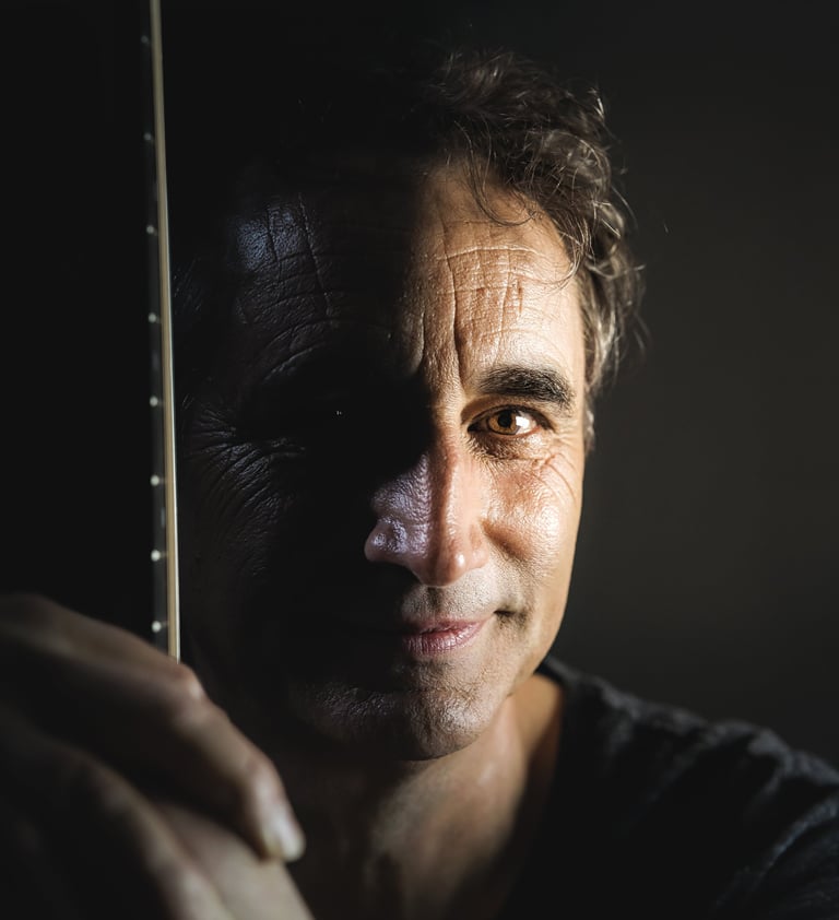 Photo de Joël Royer de face tenant sa guitare avec le manche de l'instrument devant lui