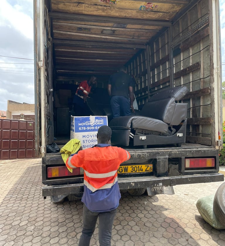 A professional mover in an orange high-visibility vest with reflective strips and blue pants, holdin
