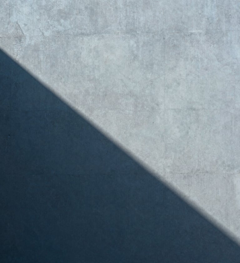 Abstract photography of light and shadow on a matte concrete surface, muted blue tones, clean composition, architectural and refined style, Global / Contemporary Art.