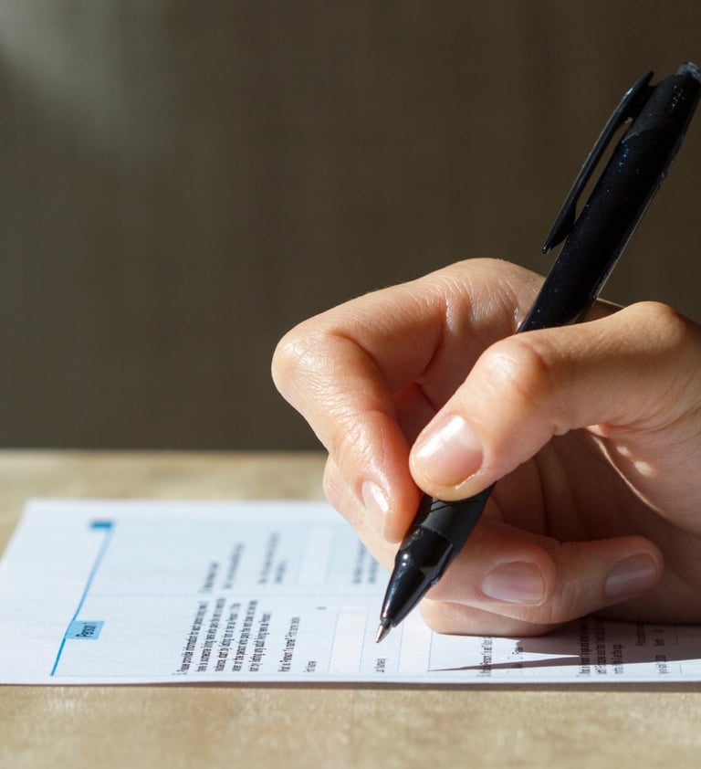 a person's hand holding a pen and writing on a piece of paper