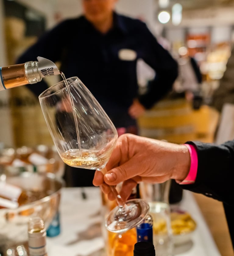 Hand of a wine professional holding out a glass which is being poured full of wine