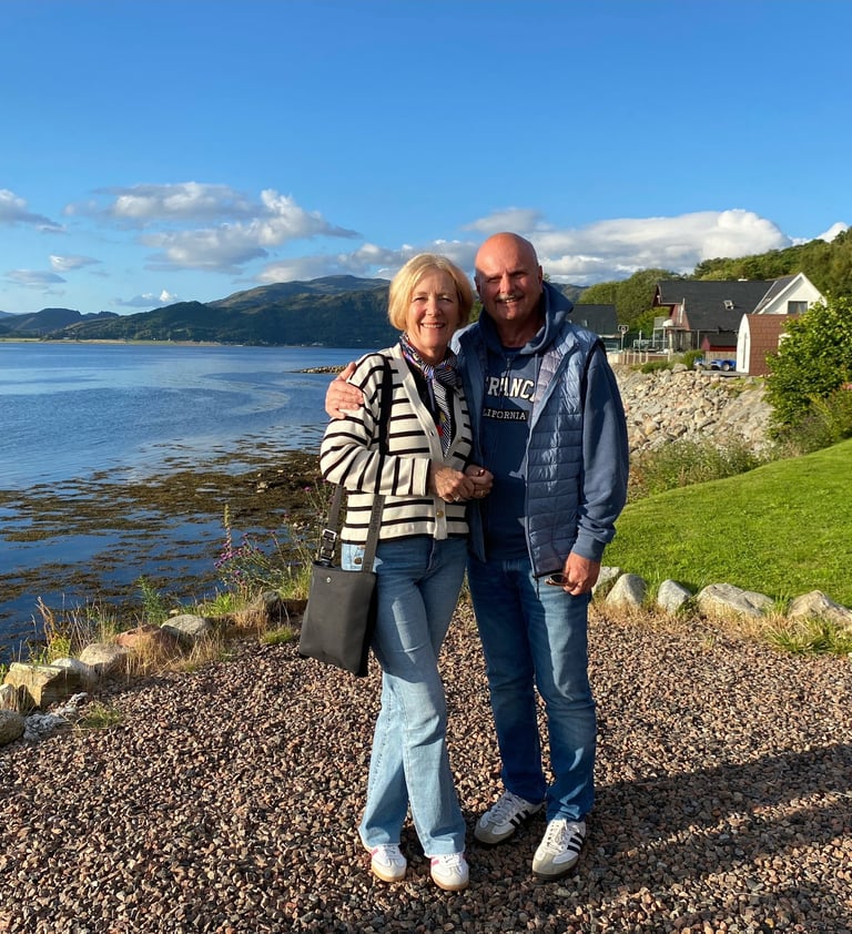 a man and woman standing in front of a lake
