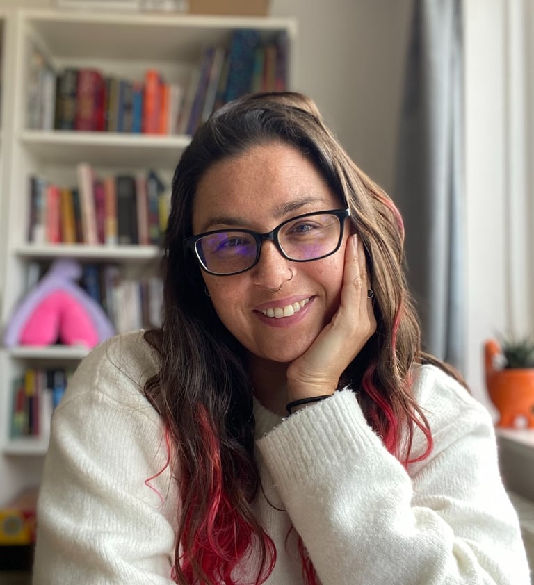 Munjeeta wears a white jumper and glasses and smiles at the camera.
