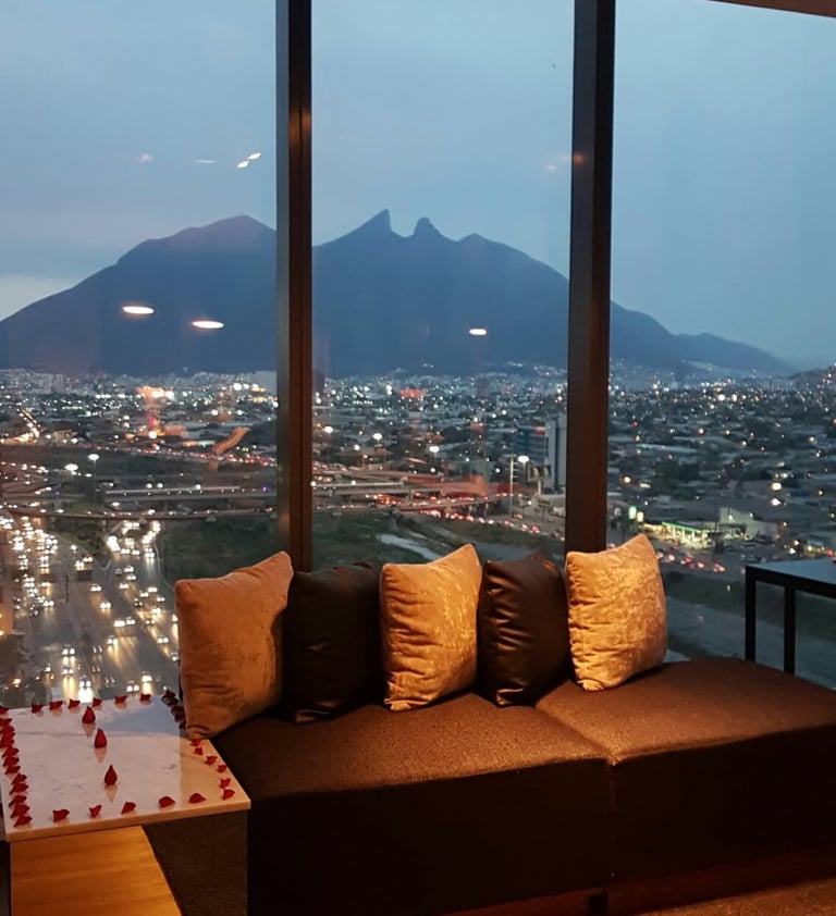 Asientos de salón de lujo con una vista panorámica de las luces de la ciudad de Monterrey y el Cerro