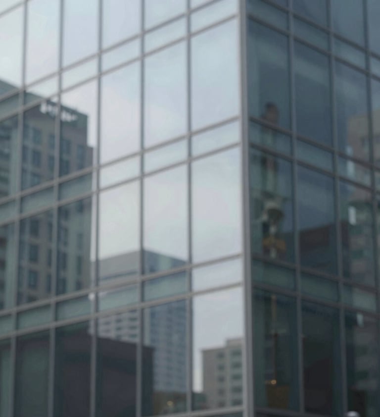 Abstract view of a glass building reflecting the surrounding urban environment. The reflection is slightly distorted, creating a painterly effect. Minimalist and elegant composition using #F5F7FA and #2F363F.