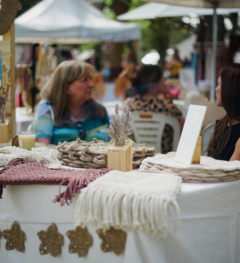 Tapices de macramé hechos a mano y decoración bohemia exhibidos sobre una mesa blanca en un mercado 