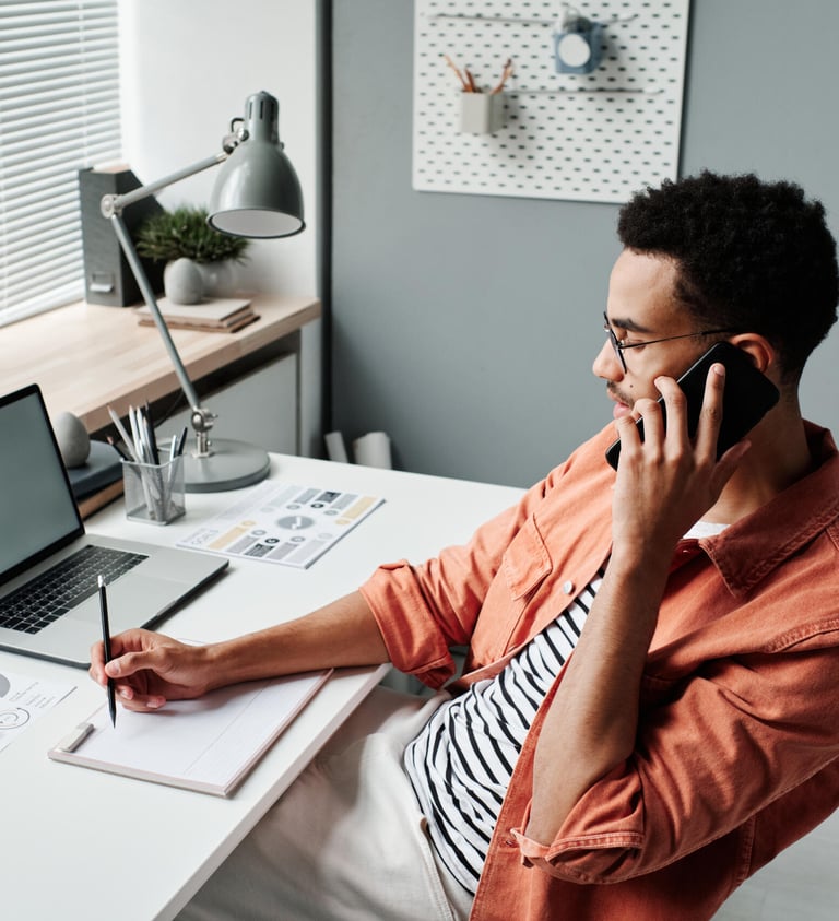 a man on a phone call  sitting at a desk 
