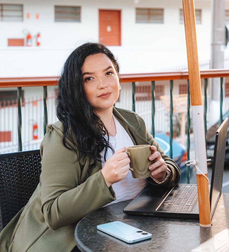 Raabe sentada com notebook segurando xícara..