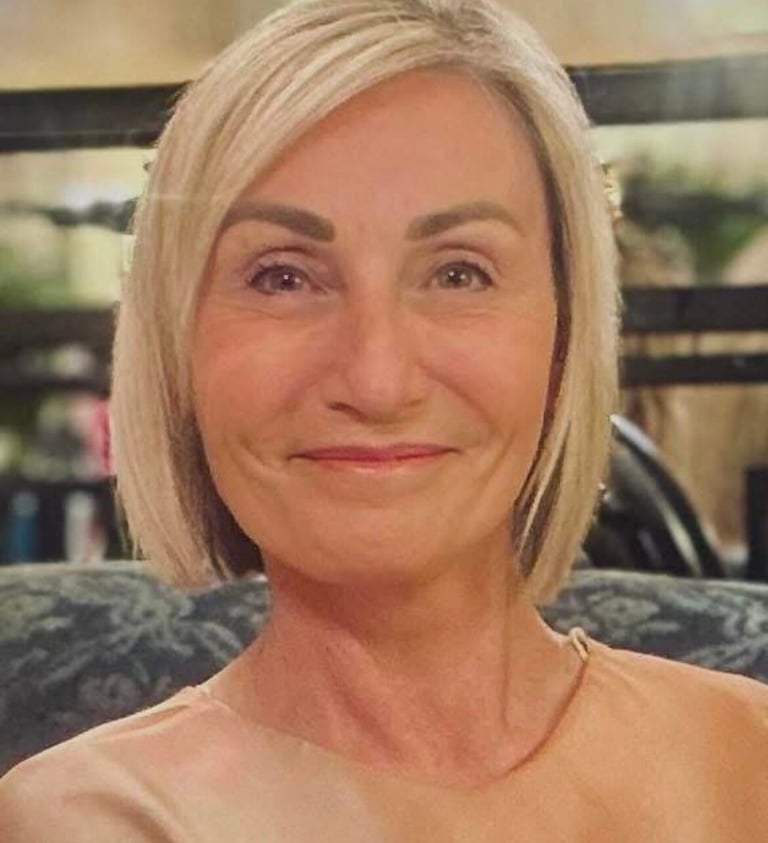 Lisa, smiling, with a blonde bob hairstyle wearing a peach-colored silk blouse.