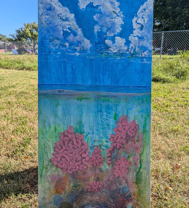 A color dense painting of a coral reef with a clouded blue sky above rendered in gloss acrylics on linen by Kathy LaFollett.