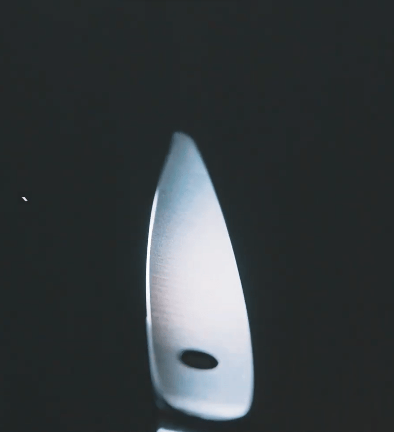 Punta de tijeras de peluquería profesionales iluminada a contraluz, mostrando precisión y acabado.