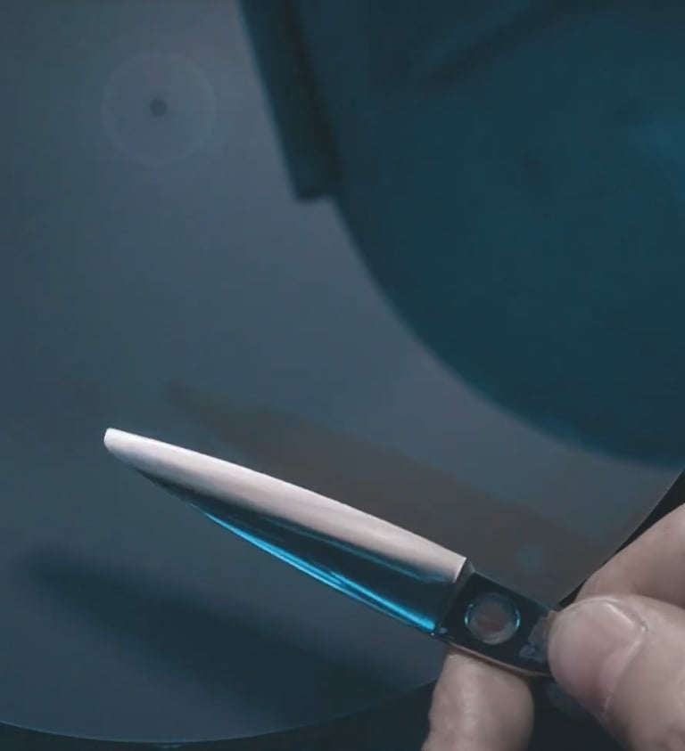 Proceso de afilado de tijeras de peluquería usando disco abrasivo de alta precisión en taller.