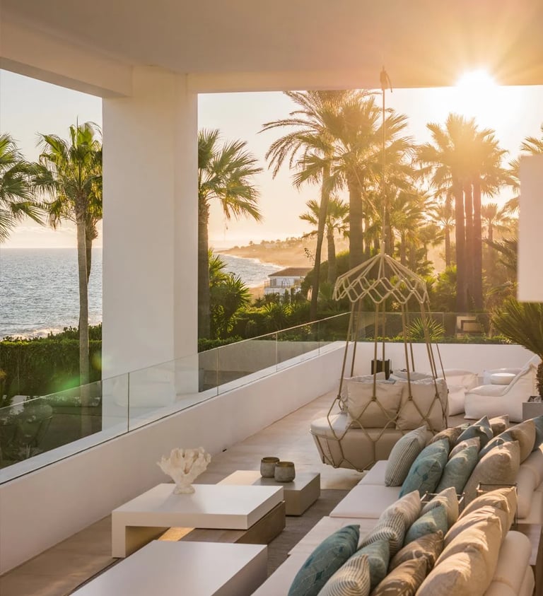 Covered terrace seating area overlooking the coastline at sunset