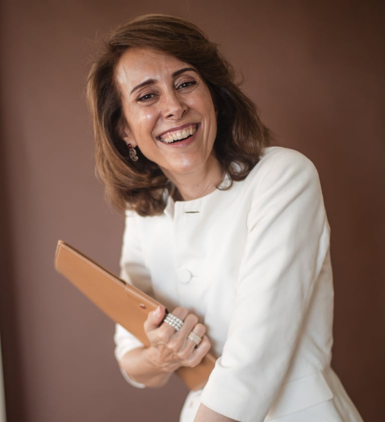 a female life coach in a white jacket holding a brown clutch