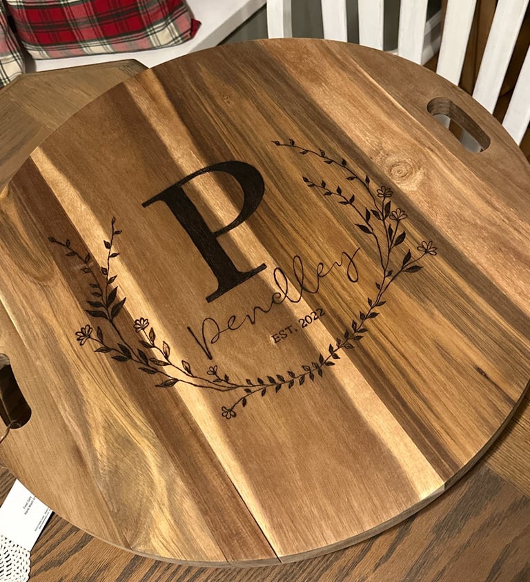 Custom engraved acacia wood serving board with personalized family name and monogram initial.