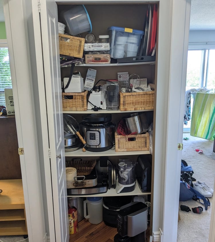 Kitchenware closet with bowed melamine shelving and disorganized clutter
