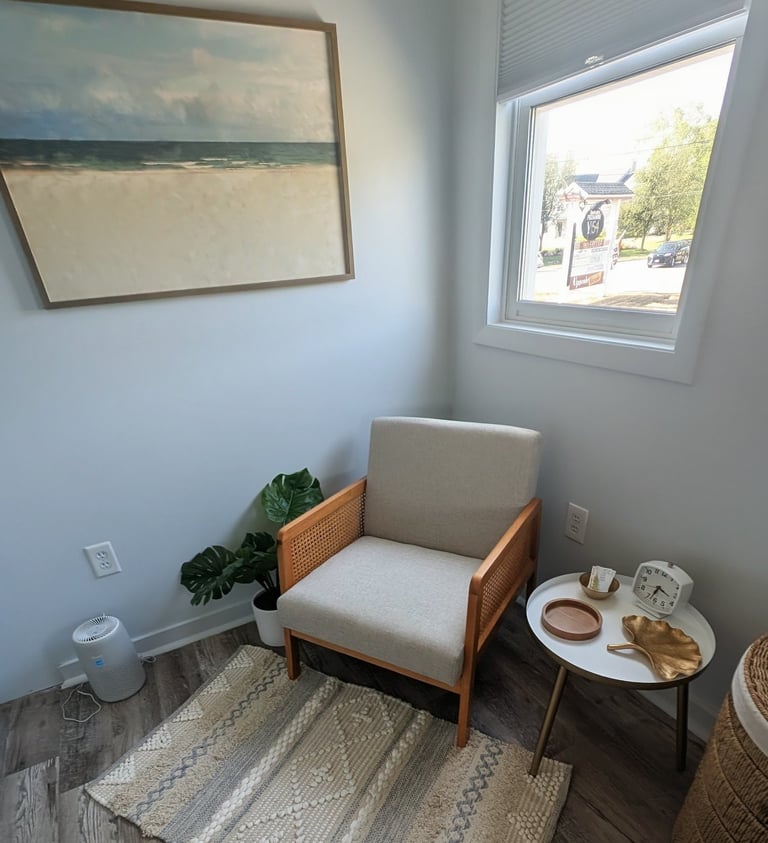 a waiting area with a chair and a table with a painting on the wall