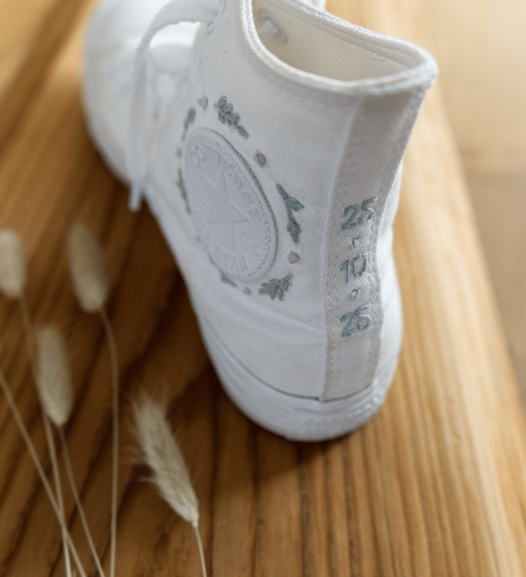 Weisser Converse mit Stickerei, Hochzeitsdatum und floralen Mustern.