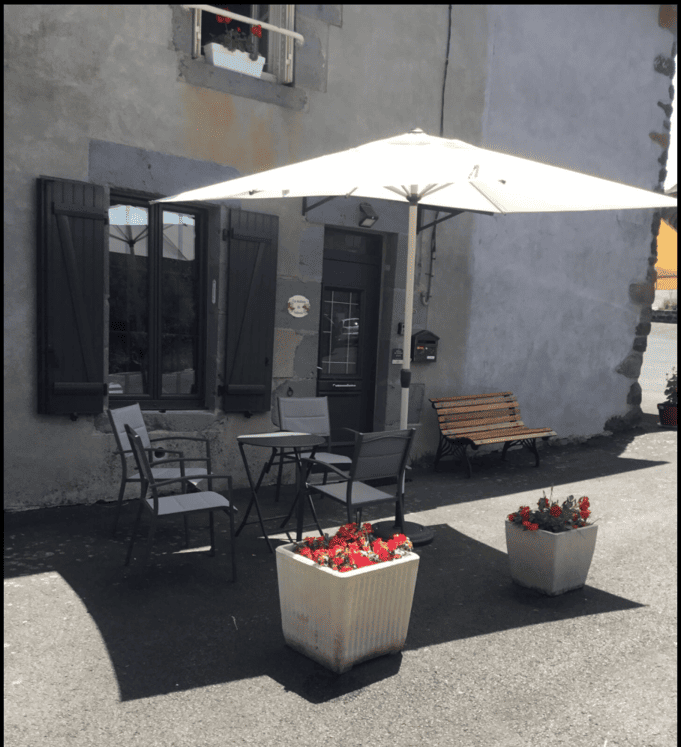 Entrée du gîte avec la table, les chaises sous un parasol