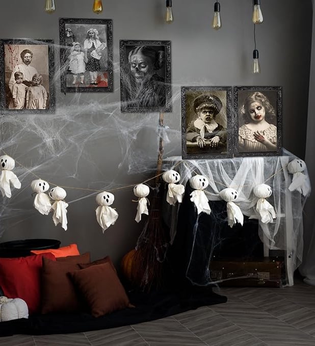 Halloween indoor decoration featuring ghost garland made of fabric hanging across a wall with spider