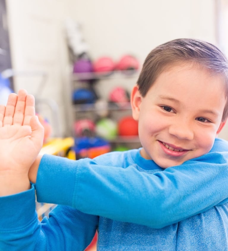 Elementary boy does a shoulder stretch.