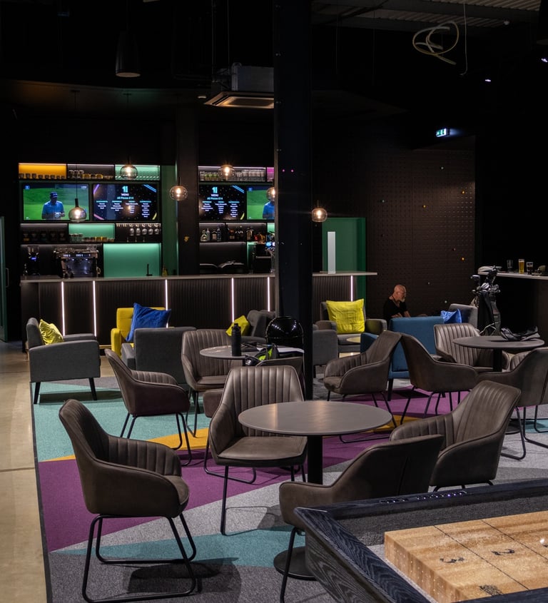 an indoor golf simulator venue with a bar, seating, shuffleboard and big screen sport