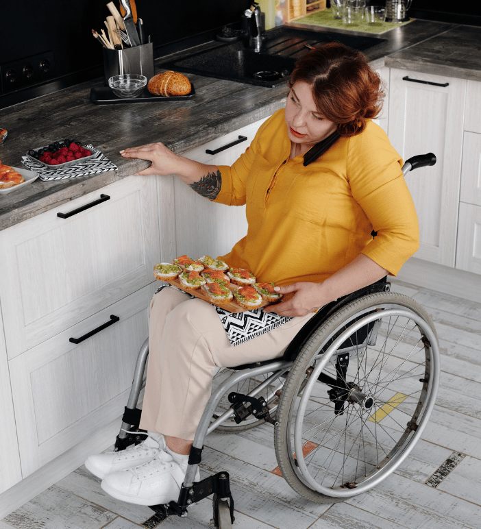a woman in a wheelchair in her kitchen with a platter of food