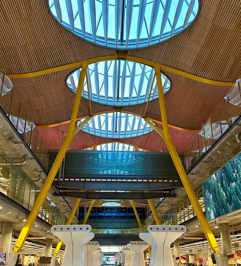 Inside Madrid-Barajas airport Terminal 4, with orange supports holding a wood and glass canopy