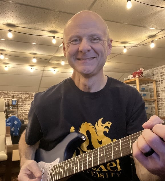 smiling man owner playing guitar