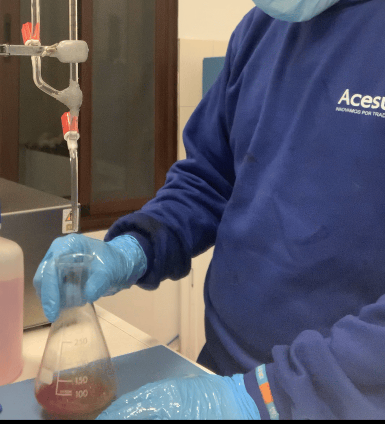 a man in a blue shirt and gloves is holding a bottle of liquid