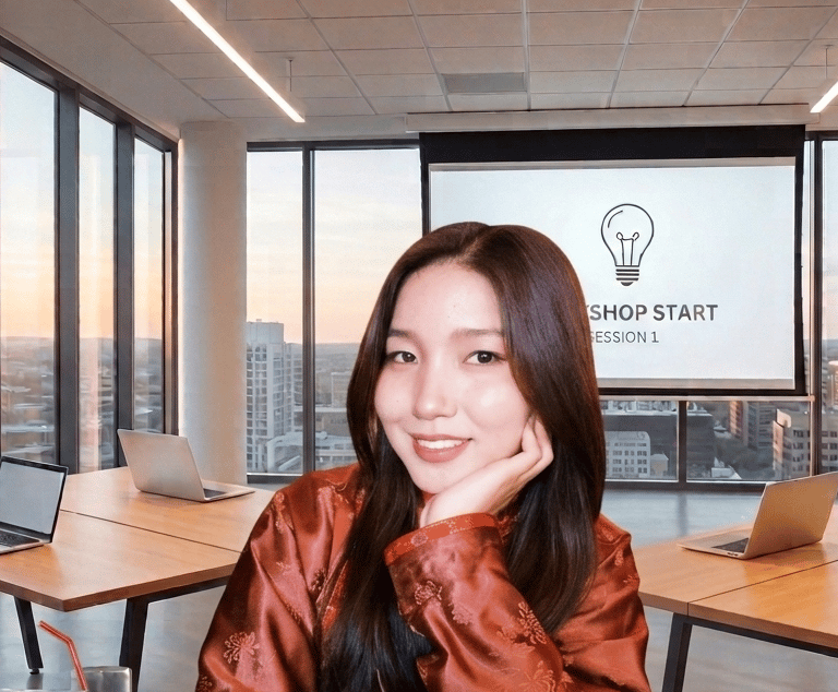 Smiling woman in a modern office workshop setting with a presentation screen and laptops.
