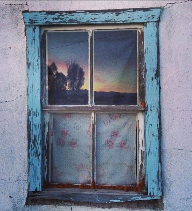 ventana azul con atardecer en el reflejo