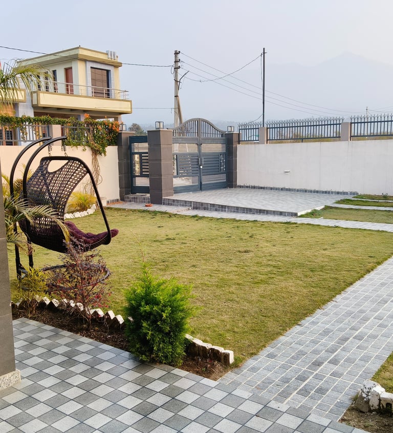 A modern garden landscape with a paved stone walkway, green lawn, and a stylish hanging egg chair.