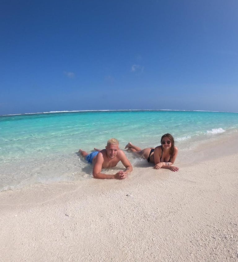 two women laying on the beach in front of a blue sky