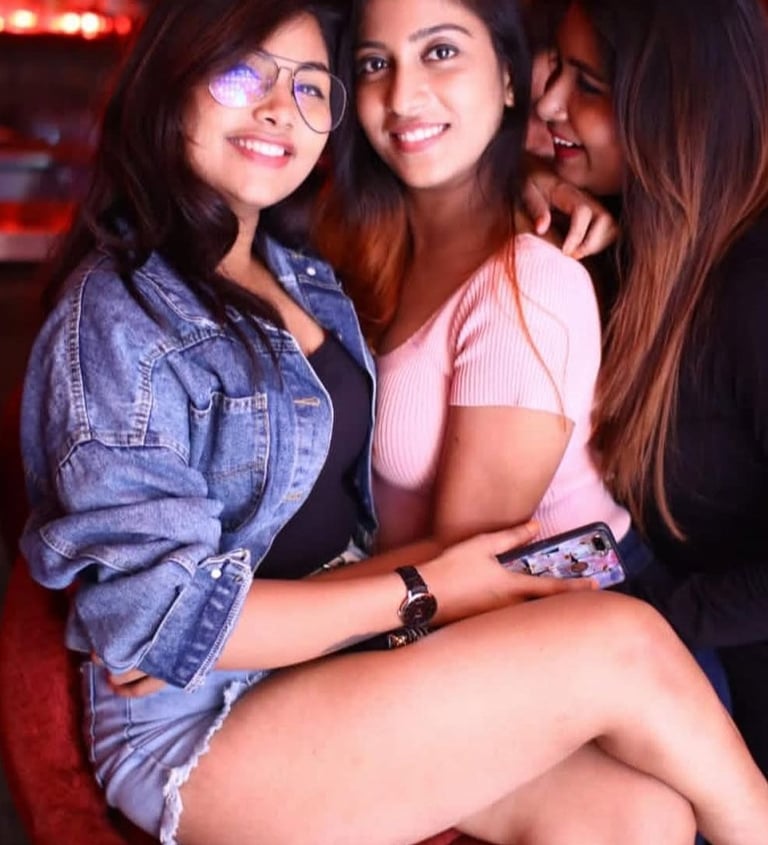 two women sitting on a red chair in a bar