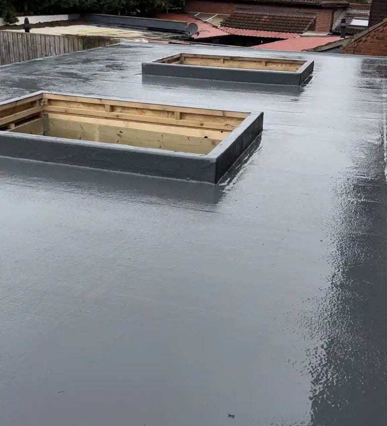 A waterproof grey GRP fiberglass flat roof installation with two rectangular skylight frames.