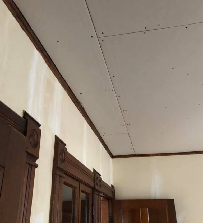 new drywall hung on ceiling of home with wood trim