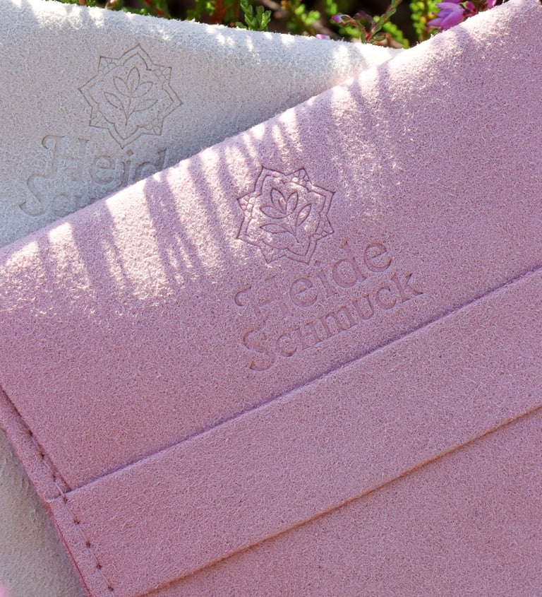 HeideSchmuck Schmuckverpackung aus edlem Samt in Rosa und Beige, fotografiert in der Heide mit blühendem Heidekraut.