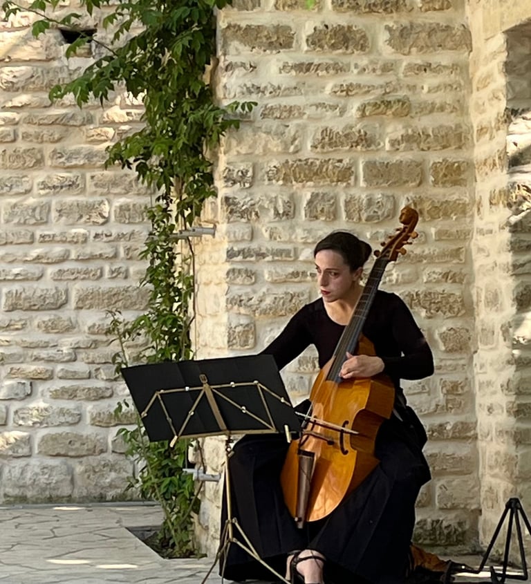 Claire playing a cello in a courtyard