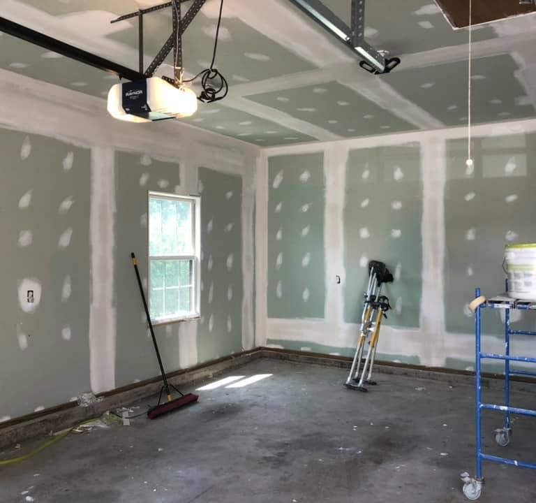 garage in the process of being drywalled with stilts and a scaffold