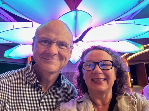 man and woman owners smiling under a flower light fixture