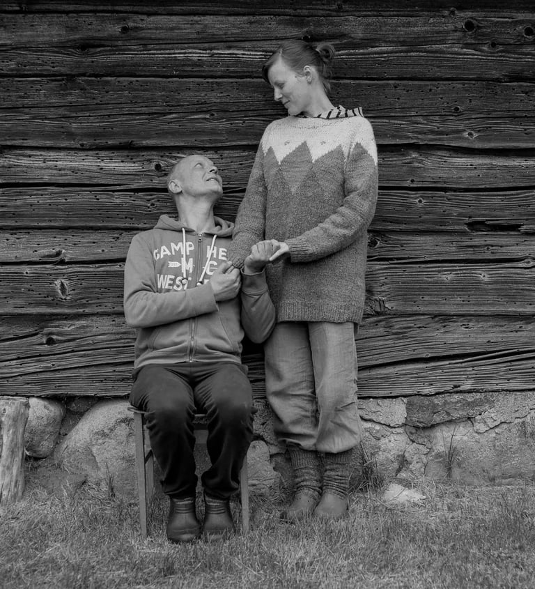 A couple seated on a chair against a wooden wall