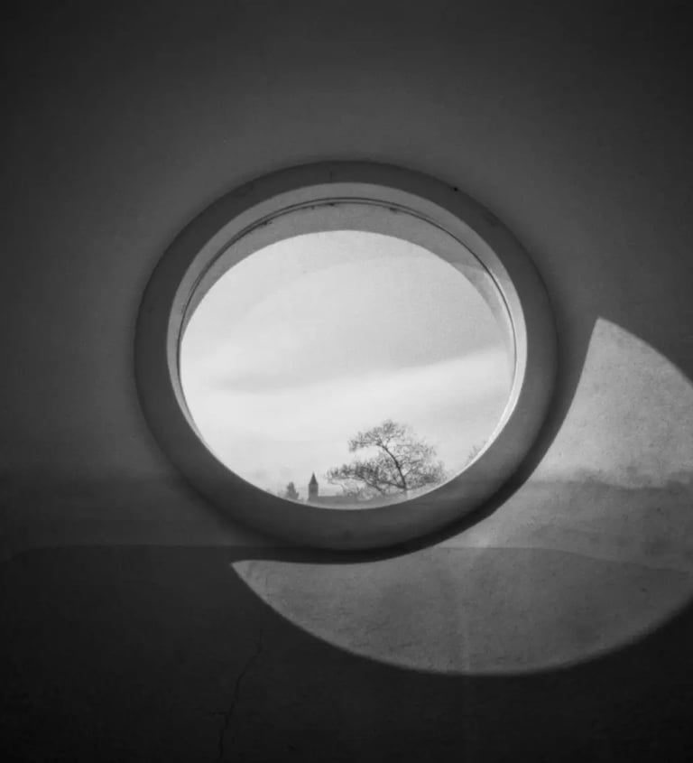 A monochrome image of a round window, showcasing contrasting shades of black and white