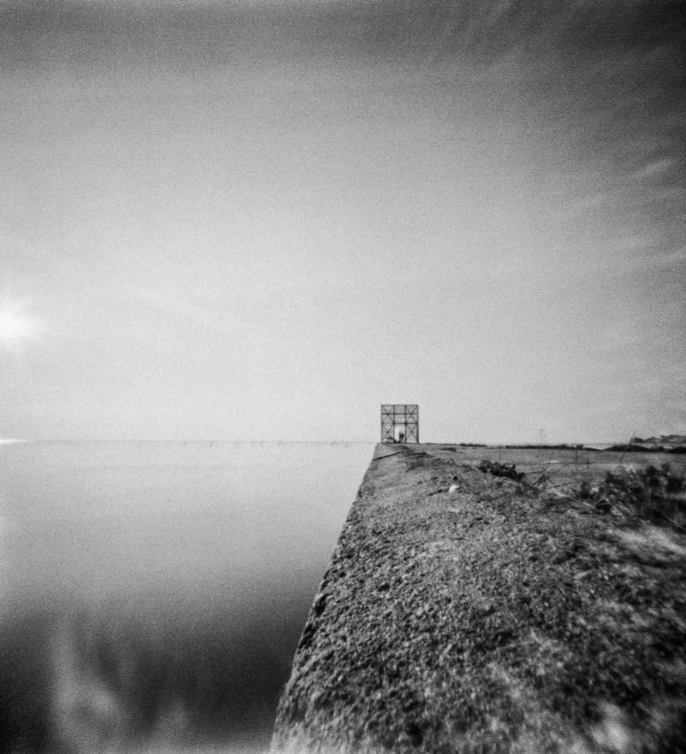 A monochrome image of a waterfront building, showcasing its architectural beauty and serene location