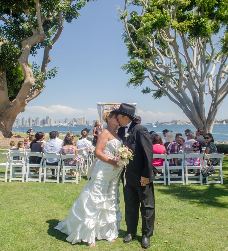 Bride & Groom kissing at wedding ceremony at Harbor Island park overlooking San Diego harbor