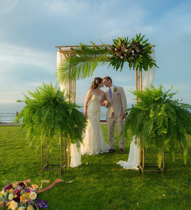 couple kissing under tropical wedding arbor at ellen browning scripps park, la jolla