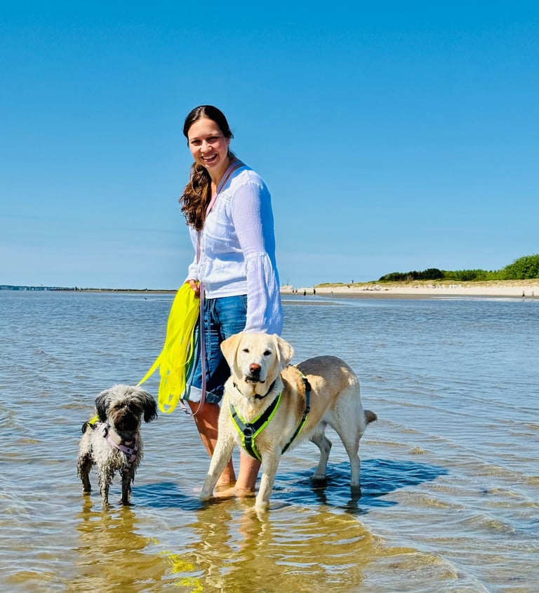 Svenja steht mit ihren Hunden Pelle und Paula im flachen Wasser der Nordsee.