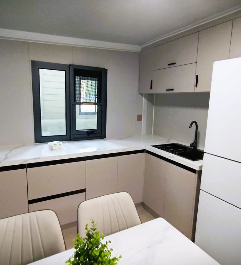 Modern minimalist kitchen with white Hisense refrigerator, marble countertops, and beige cabinets.