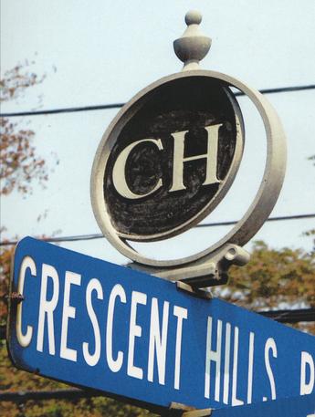 A Street sign of Crescent Hills Rd showing a logo mounted on top with the letters C H