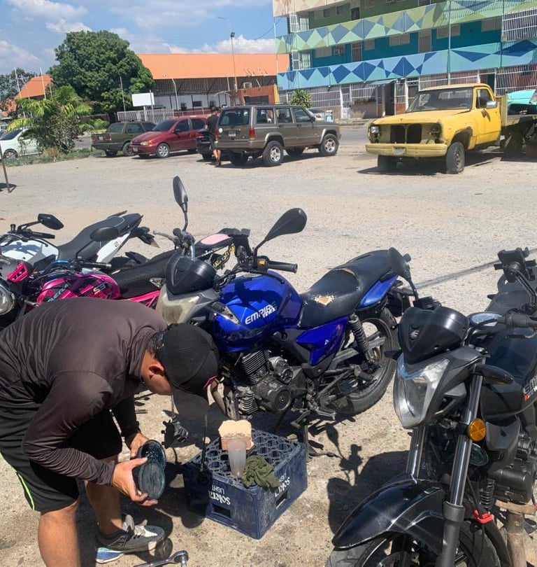 Un mecánico realiza mantenimiento a varias motocicletas Empire Keeway estacionadas en un lote